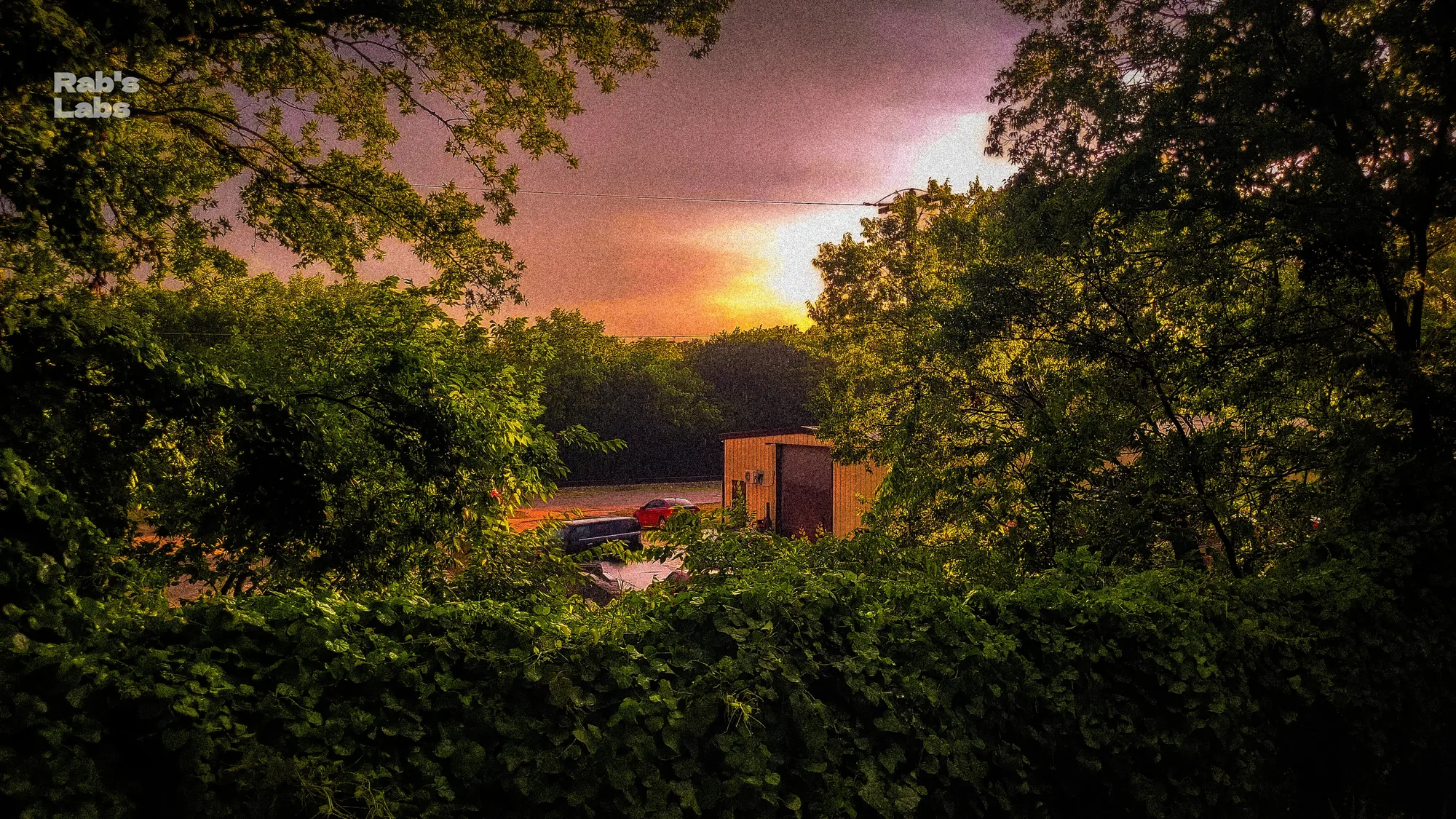 Sunset over a wooded neighborhood beneath dramatic clouds