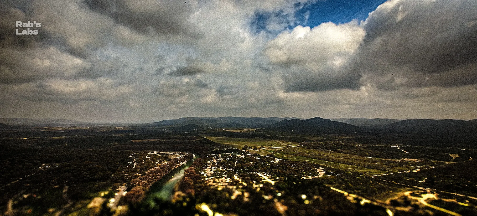 Panoramic hill country view beneath textured clouds